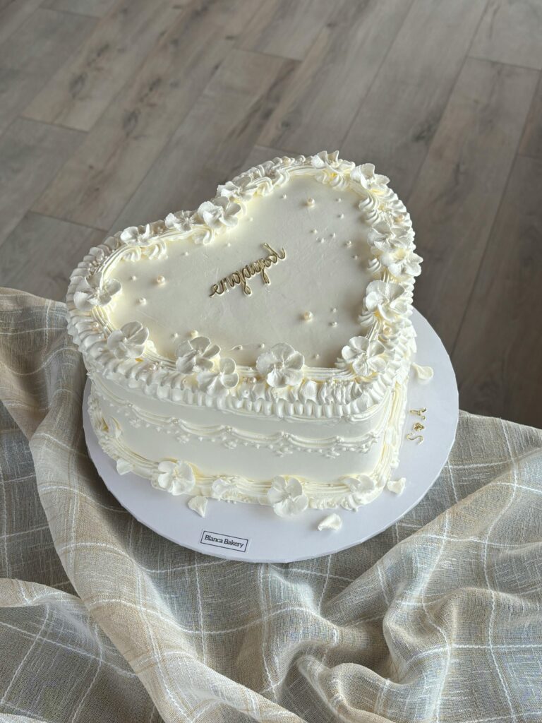 Heart-shaped white cake with floral decorations, perfect for weddings or anniversaries.